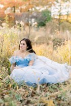 Doan Phuong in blue dress seated in grassy field