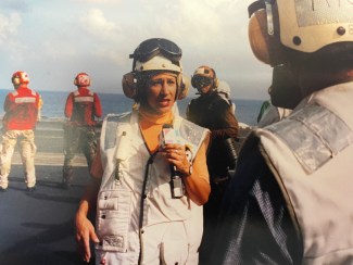 brown skinned female tv reporter on a US Navy carrier