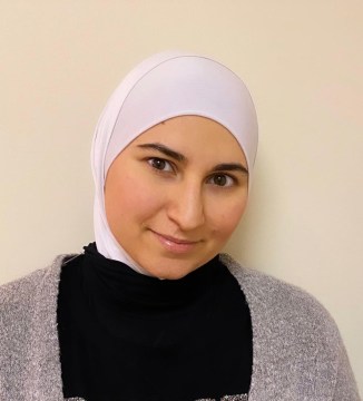 Muslim woman in white head covering smiling at camera