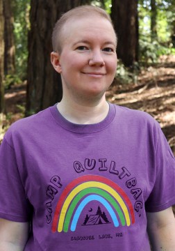 author headshot person wearing purple camp QUILTBAG tshirt