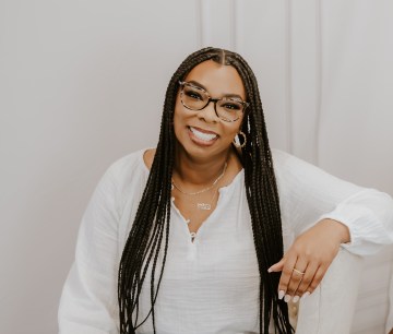 Author headshot - a smiling Black Panamanian author with long dark braids, wearing glasses.