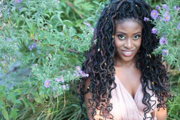 author headshot - black woman with long curly braids framed by flowering plants